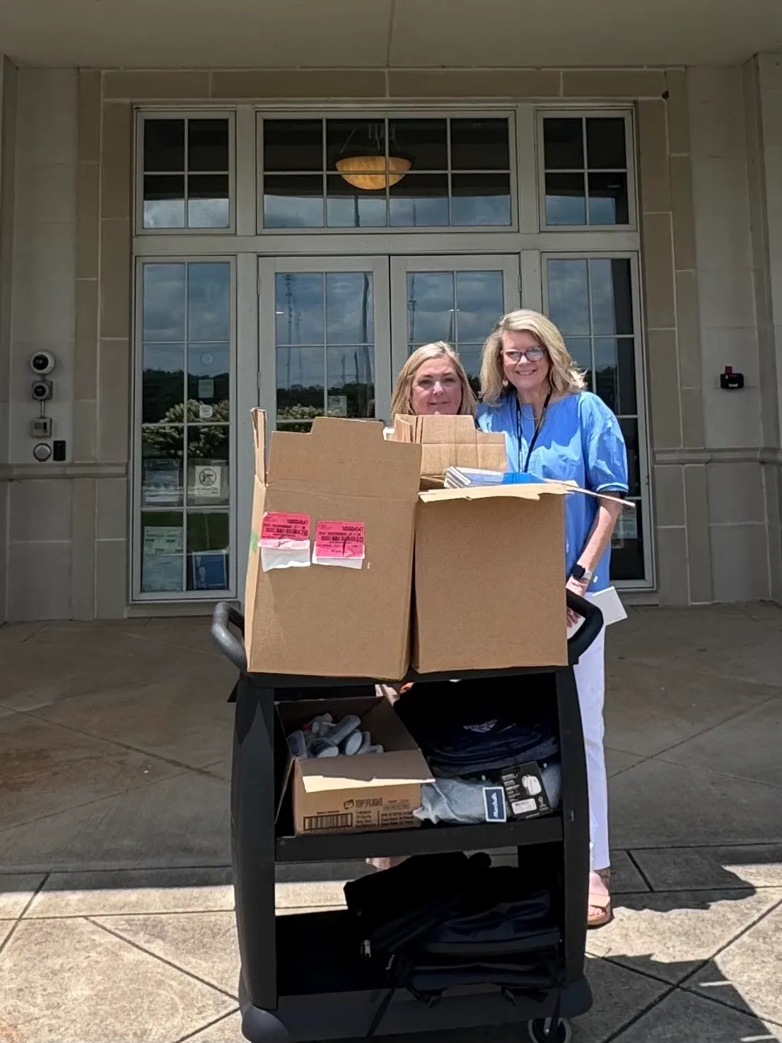 Pair standing with supply cart outside entrance