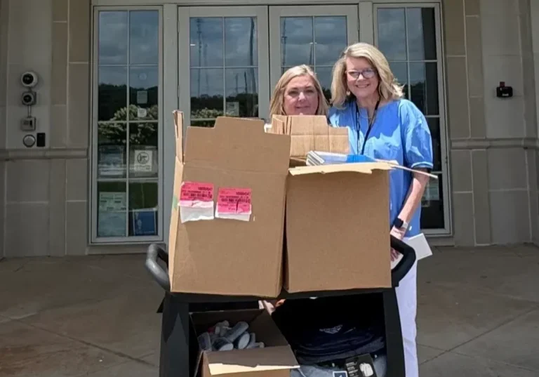 Pair standing with supply cart outside entrance